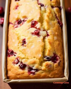 a loaf of cranberry bread sitting in a pan on top of a wooden table