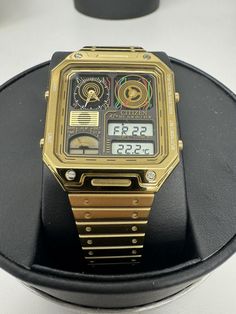 This stylish Citizen watch features a gold-toned bracelet and square-shaped multicolor case, with a black analog and digital display. The watch is equipped with a perpetual calendar and chronograph features. It has a case size of 33mm, case thickness of 9mm and a lug width of 15mm, making it the perfect dress/formal watch for men. The Citizen Star Wars C-3PO JG2123-59E wristwatch is water-resistant up to 50 meters and has a fixed bezel type. The watch comes with its original box/packaging, but without papers or manuals. It has a deployant closure and can fit a maximum wrist size of 7.26-7.5 inches. The watch is from the 2010-now collection and is not vintage. This timepiece is perfect for any Star Wars fan and is sure to make a great addition to any collection. WATCH WAS STORE DISPLAY WITH Gold Digital Watch With Subdials, Retro Watch Accessories With Analog Display, Retro Gold Watches With Subdials, Gold Retro Watches With Subdials, Retro Watch Accessories With Rectangular Analog Dial, Retro Watch Accessories With Analog Display And Rectangular Dial, Formal Watch, Citizen Watch, Perpetual Calendar