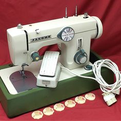 an old sewing machine sitting on top of a green box next to some white buttons