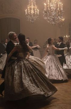 two people in formal dress dancing with chandeliers hanging from the ceiling behind them