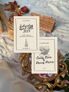 two wedding programs sitting on top of a table next to bread and other food items