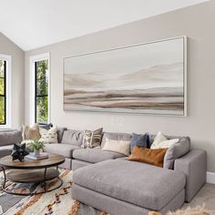 a living room filled with lots of furniture and large paintings on the wall above it