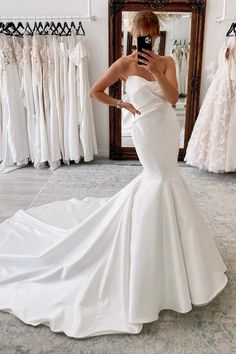 a woman in a white wedding dress taking a selfie with her cell phone while standing in front of a mirror