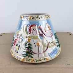 a ceramic vase sitting on top of a wooden table covered in snowmen and trees