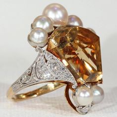 "I wanted something fun, something fresh, something subtle. Then I saw this pearly citrine crown ring and decided that \"subtle\" was no longer in my vocabulary. This piece is an assemblage of beauty, a collection of gems fit for a king. Honestly, I have no regrets. This regal ring features a large calf cut citrine stone topped with a crown of beautiful white pearls accented with diamonds. The stones in this ring are set in platinum with an 18 karat gold back and shank. The lively citrine is a v Elegant Formal Topaz Ring With 17 Jewels, Elegant Multi-stone Citrine Topaz Ring, Elegant Multi-stone Topaz And Citrine Ring, Elegant Multi-stone Citrine Rings, Elegant Pear-shaped Topaz Ring For Gift, Elegant Multi-stone Topaz Ring In Yellow Gold, Luxury Citrine Wedding Rings, Elegant Multi-stone Yellow Gold Topaz Ring, Elegant Multi-stone Topaz Ring As A Gift