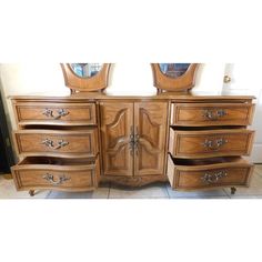 a wooden dresser with two mirrors on top of it