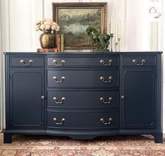 a blue dresser with gold handles and knobs on it's drawers in a living room