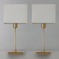 two lamps are sitting side by side on the wall, one has a white shade