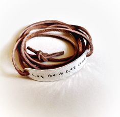 "Wear your daily affirmations and inspirational words on your wrist to remind yourself of what is most important to you every day. :) This leather wrap bracelet features the phrase \"Let Go and Let God\", hand stamped onto hammered aluminum. The soft brown faux suede leather cord is approximately 36\" long and can usually wrap around the wrist 2 times. The. Just tie a loose knot or two in the back to secure and you are good to go! You can have this bracelet with or without the tiny cross at the Inspirational Engraved Bracelets For Everyday, Everyday Inspirational Engraved Bracelets, Inspirational Engraved Everyday Bracelets, Adjustable Spiritual Hand Stamped Bracelets, Spiritual Adjustable Hand Stamped Bracelets, Inspirational Adjustable Stamped Bracelets, Adjustable Stamped Meaningful Bracelet, Meaningful Adjustable Stamped Bracelets, Inspirational Stamped Bracelets For Friendship