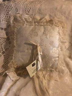 a white pillow with lace on it and a tag hanging off the side of it