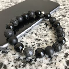 Lava Stone, Matte Black Onyx, And Onyx 10mm Bracelet w/ Silver Accents Mixed, matched, and designed with a variety of elegant beads for a graceful look. This is a beautiful piece made to be worn separately or combined with our other Embody'd Art pieces! This bracelet can also be worn as an oil diffuser. Just add one drop of your favorite oil to the AAA grade lava beads and you're set to go. This bracelet is crafted with quality elastic stretch cord. This bracelet is also designed to fit snug on Adjustable Black Beaded Bracelets With Polished Beads, Adjustable Black Wristband With Gemstone Beads, Black Beaded Bracelets With Spacer Beads As Gift, Adjustable Black Stretch Bracelet With Spacer Beads, Adjustable Black Gemstone Beaded Bracelets, Black Beaded Stretch Bracelet, Black Adjustable Stretch Bracelet With Gemstone Beads, Black Stretch Bracelet With Spacer Beads As Gift, Black Stretch Bracelet With Polished Beads