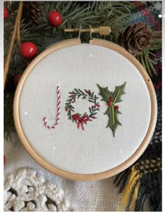 a cross stitch christmas ornament with holly and candy canes in the hoop