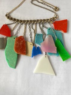 a multicolored necklace with multiple pieces of glass hanging from it's chain