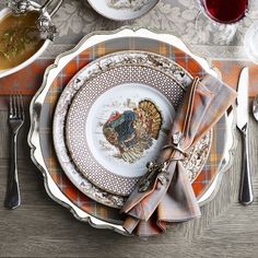 a table set for thanksgiving with turkey plates and silverware