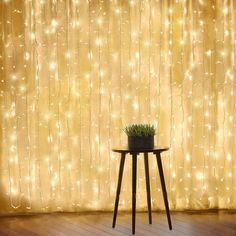 a table with a potted plant on it in front of a curtain