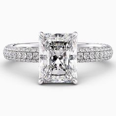 a princess cut diamond ring with pave set diamonds on the shoulders and sidestones