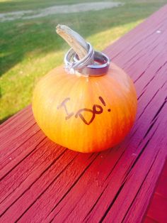 an orange pumpkin with the word boo written on it sitting on a red picnic table