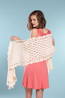 a woman holding up a crocheted shawl in front of a blue background