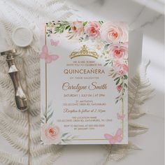 a wedding card with pink flowers and gold foil on it next to a pair of scissors