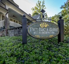 the black walnut bed and breakfast inn sign in front of its building with bushes surrounding it