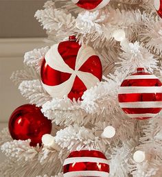 a white christmas tree decorated with red and white ornaments, candy cane ornament