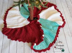 a crocheted christmas tree skirt is on the floor next to a small fir tree