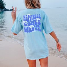 "Experience the essence of carefree living with our \"Happiness Comes In Waves\" Comfort Colors Oversized Beach Tee. Crafted for the trendy and free-spirited woman, this shirt features a captivating wave design on the front, symbolizing life's ebbs and flows. Made from premium Comfort Colors fabric, renowned for its softness and durability, this shirt is perfect for beach days, lake trips, and cruises. Its vintage boho charm adds a timeless touch, while the Y2K-inspired design speaks to modern t Oversized Graphic Print Beach Shirt, Oversized Graphic Print Vacation Shirt, Oversized Graphic Print Shirt For Beach, Oversized Vacation Shirt With Letter Print, Oversized Graphic Print Shirt For Vacation, Oversized Letter Print Shirt For Vacation, Oversized Summer Tops For Leisure, Oversized Short Sleeve Shirt For Beach Season, Oversized Relaxed Tops For Beach Season