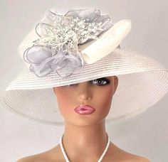 The featured hat is a light weight light silver straw hat with a tiny bit of sparkle to the hat. The band around the hat is a bright sparkly silver bling strip. A group of silver grey organza petals look soft and whimsical against a background of  large ivory crinoline bow. In the center of the design is a large metal wired flower with marquis clear rhinestones and clear crystal beads are attached by wires that moves a bit when the hat moves. This motion making all the crystals sparkle. Grey sparkle sinamay loops are placed at the sides of the design. The hat is so dramatic and evocative it's a must have for any woman who loves hats. Creating the look that suits you best comes from turning the hat on your head creating a different look with each twist till you find the look you love. This Audrey Hepburn Hat, Classy Hats, Silver Bling, Easter Hats, Tea Party Hats, Kentucky Derby Hat, Elegant Hats, Church Hats, Love Hat