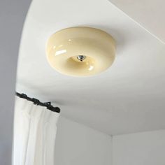 a light that is on the ceiling in a room with white walls and drapes