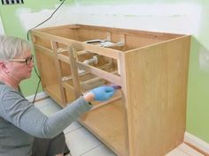 a woman kneeling down in front of a cabinet that has been built into the wall