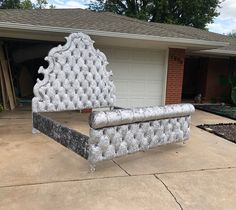 a white bench sitting in front of a house next to a driveway with a garage behind it