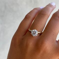 a woman's hand with a diamond ring on top of her finger and the other hand holding an engagement ring