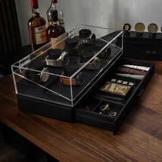 an assortment of watches and other items in a case on top of a wooden table