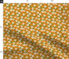 an orange and white flowered fabric with green dots in the center, on a ruler