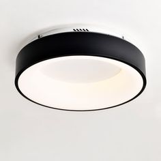 a black and white circular light fixture on the ceiling in a room with white walls