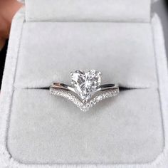 an engagement ring with a heart shaped diamond on it in a white velvet presentation box