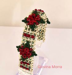 red and white flowers are attached to the side of a plastic tube with beads on it