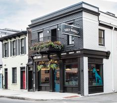 an old building with plants growing out of it's windows on a street corner