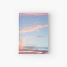 the sky is pink and blue with clouds in it hardcover book on a white background