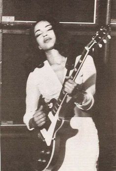 an old photo of a woman playing a guitar