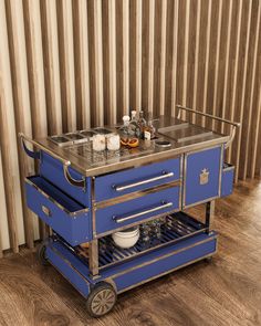 a blue cart with two sinks and some bottles on the top is sitting in front of a striped wall