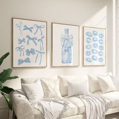 three blue and white paintings hang on the wall above a couch in a living room