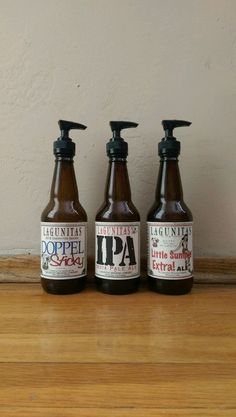 three bottles of liquid sitting on top of a wooden table