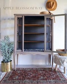 an old fashioned armoire is sitting in the corner of a room next to a potted plant