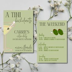 the wedding stationery is set up next to some white flowers and green cards with wine glasses on them