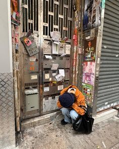 a man squatting down in front of a building with lots of papers on it