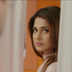 a young woman looking out the window in front of her is an orange wall and she has long brown hair