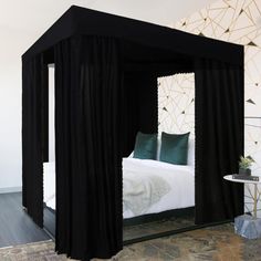 a black canopy bed in a bedroom next to a wall with geometric designs on it