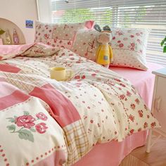 a bedroom with pink and white bedding, flowers on the comforter and pillows