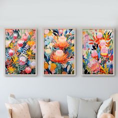 three floral paintings hang on the wall above a couch